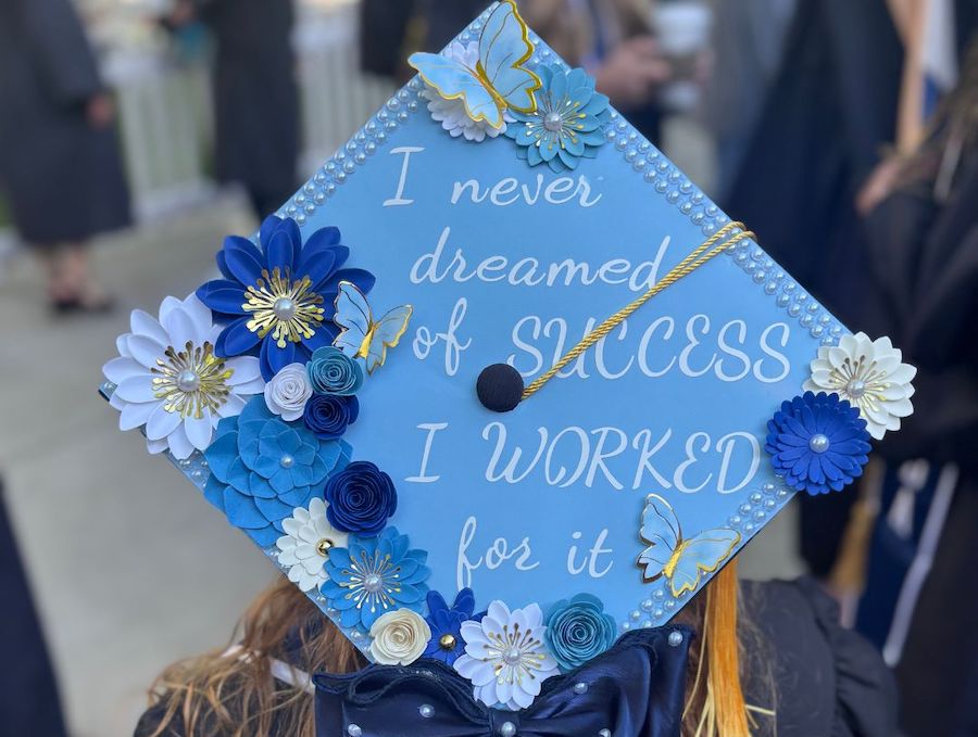 A decorated graduation cap in blue with flowers that reads "I never dreamed of success I worked for it."