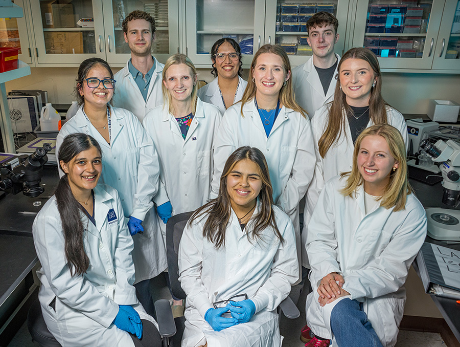 Students in labcoats and goggles in the lab.