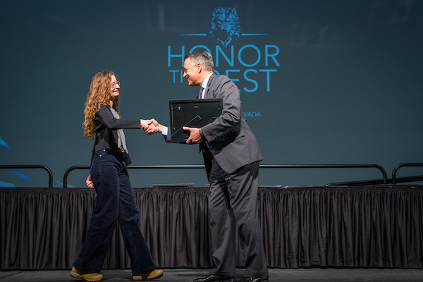 Professor Leger walks across the stage to shake hands with President Sandoval.