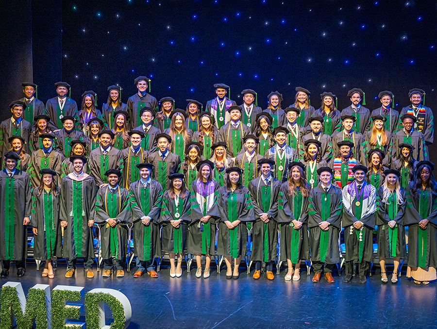 The 59 M.D. Class of 2025 graduates posing on stage.