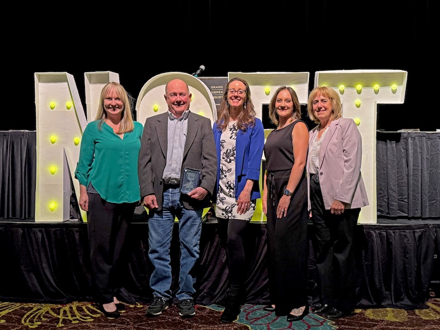 Nevada Tech Hub team at NCET awards in front of a decorative NCET sign.