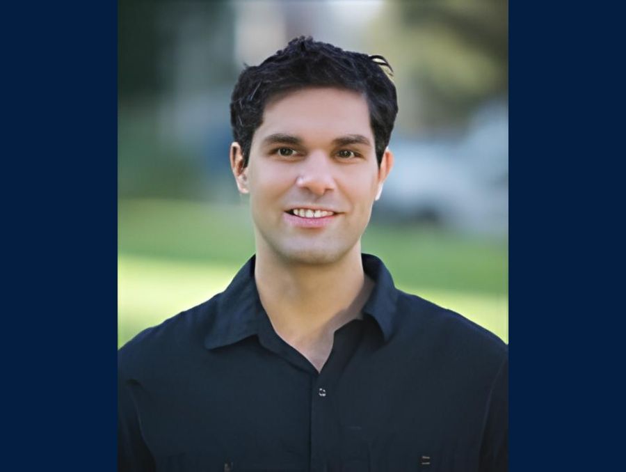 A headshot of a smiling man.