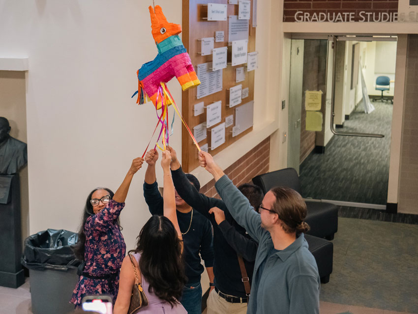 Students and faculty gather around to break a piňata in celebration.