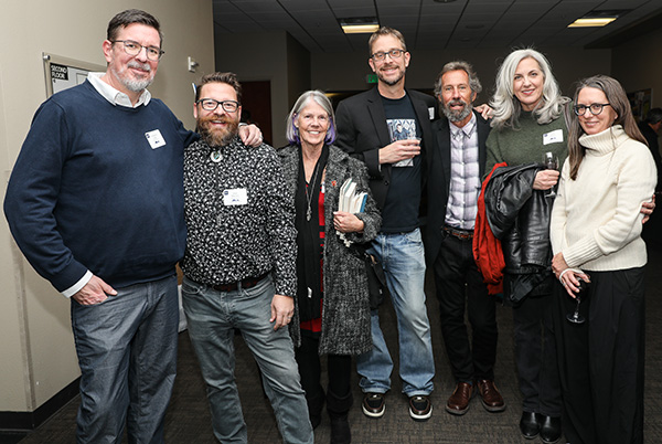 A group of four men and three women friends and writers gather, standing arm-in-arm, together, for a group photo at the 2024 Nevada Writers Hall of Fame.