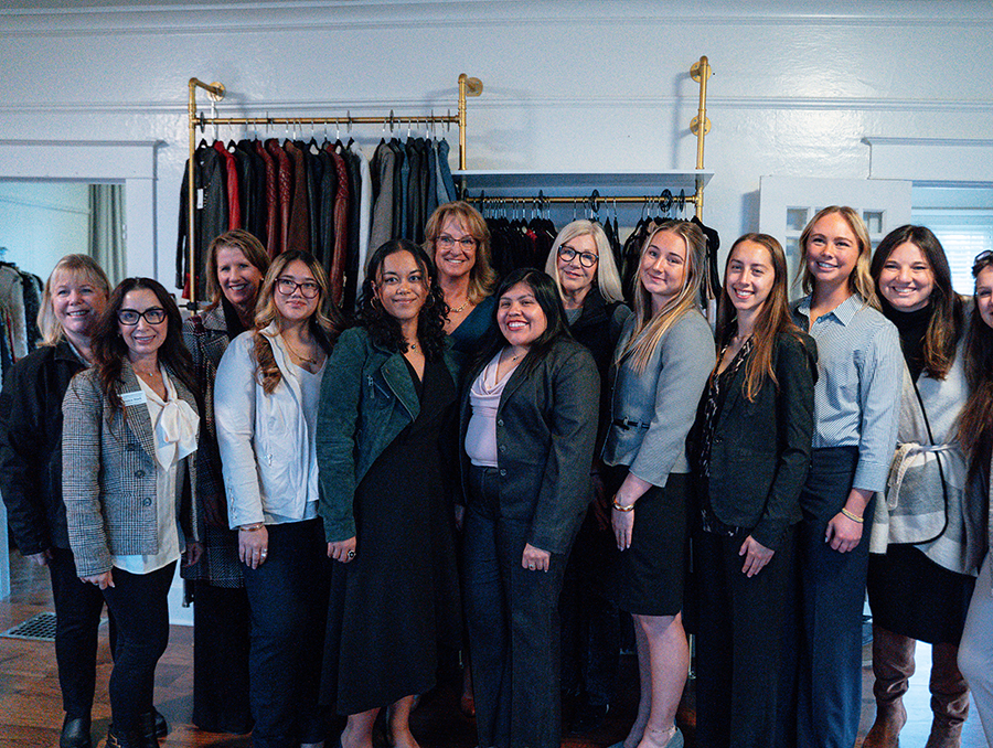 A group photo of about twelve women standing in business attire.