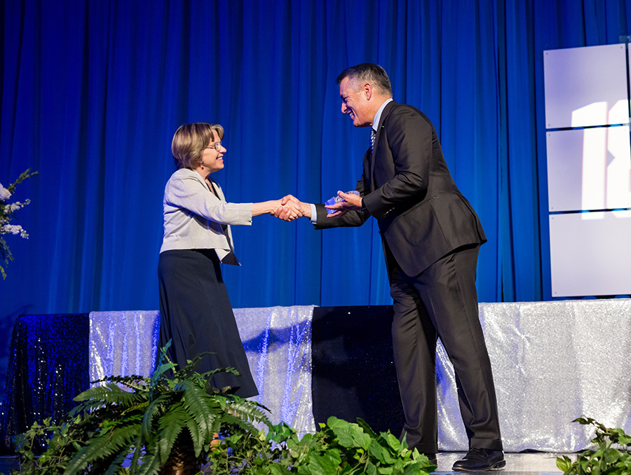 Dr. Debra Hendrickson received the Distinguished Alumna award from University President Brian Sandoval on stage during a ceremony.