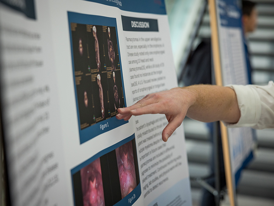 A hand pointing at a poster with research findings.