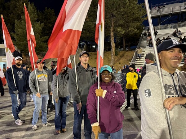 Niccole Callahan holding flag for salute to service football game along with other student veterans.