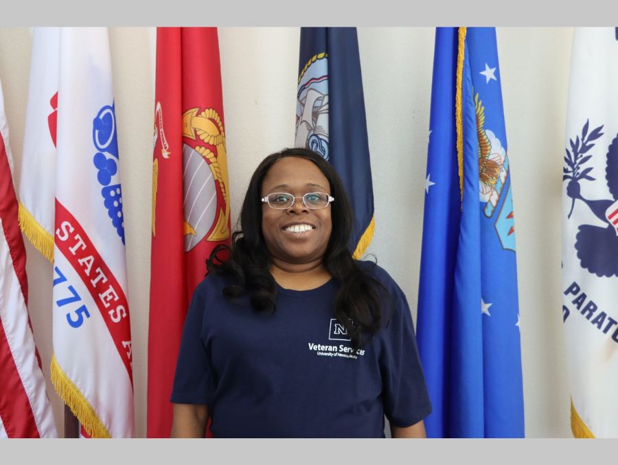 Niccole Callahan posing in front of military branch flags.