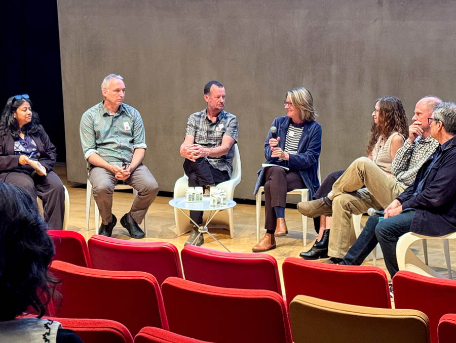 Interdisciplinary panelists sit onstage discussing their research.  