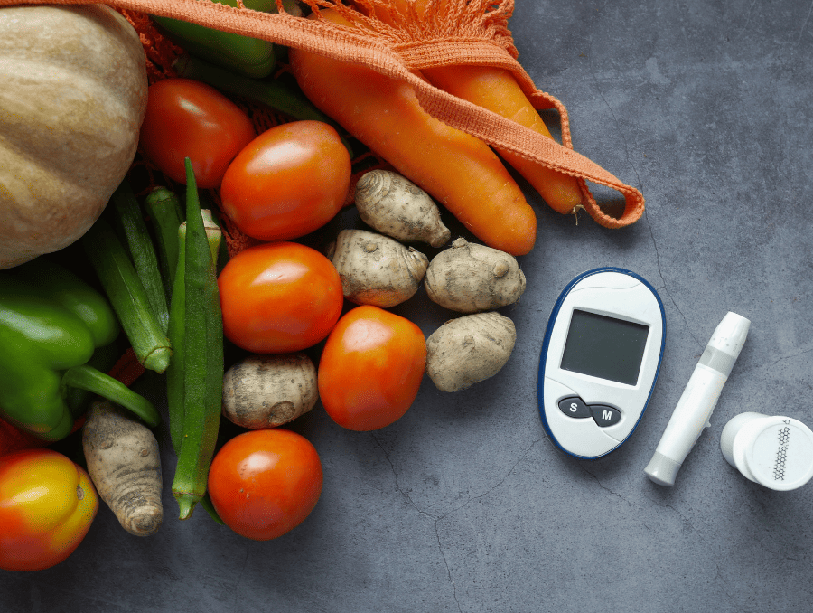 A glucose monitor next to vegetables including tomatoes and potatoes.