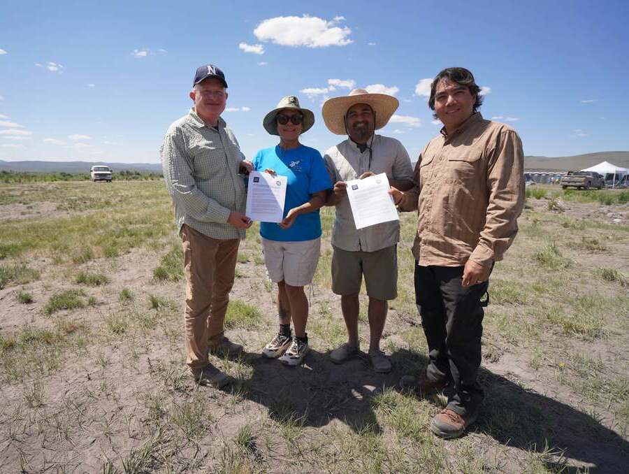 University and Tribal stand outside, holding signed MOU.