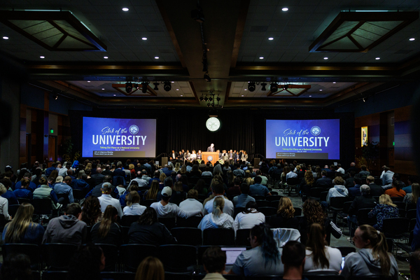 The large crowd gathered and seated in the ballrooms, listening to the address with President Sandoval at the podium.