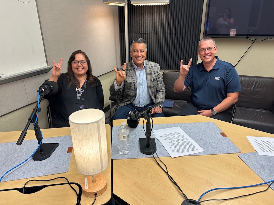Daphne Hooper, President Sandoval and Fred Steinman holding Wolf Pack hand signs up while in the recording studio.