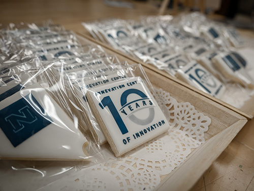 Commemorative cookies celebrating '10 Years of Innovation' at the Invention Center, wrapped in clear plastic and arranged on a wooden tray.