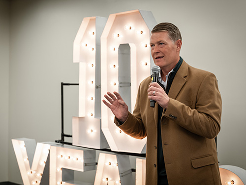 EDAWN CEO Taylor Adams speaking into a microphone next to a large lit sign that reads "10 YEARS."