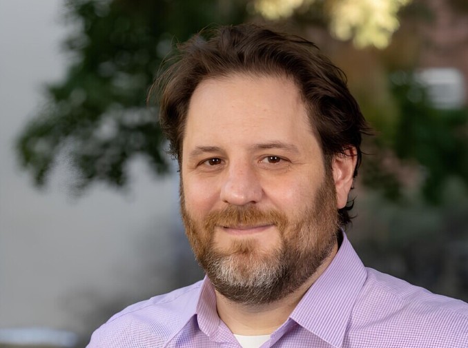 A headshot of a smiling man.