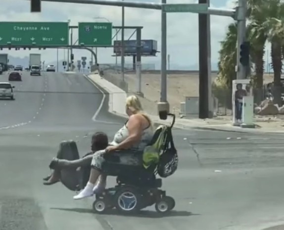 A person in a wheelchair crossing a busy road.