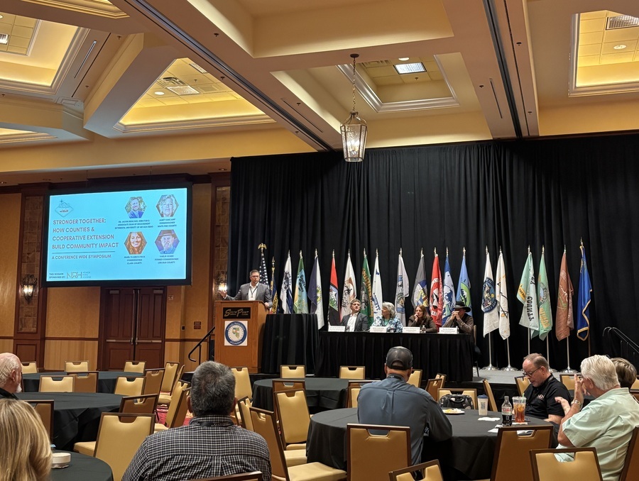 A man on a platform addressing a group of listeners.