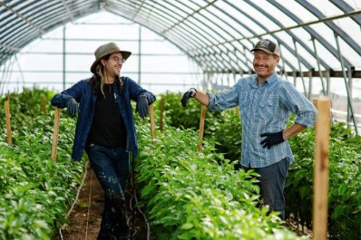 Two men standing in a hoop house.