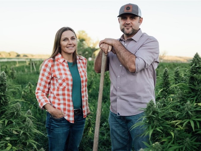 A woman and man standing in a field of hemp.