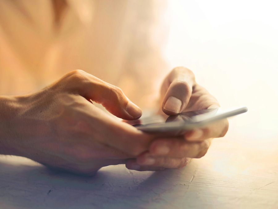 Hands holding a touchscreen phone.