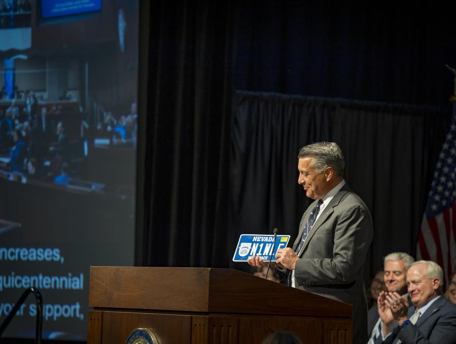 President Sandoval holding the sesquicentennial license plate. 