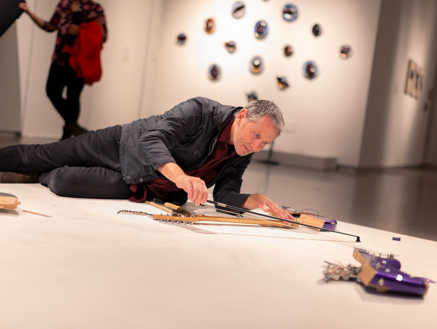 A man playing a violin attached to a floor canvas. 