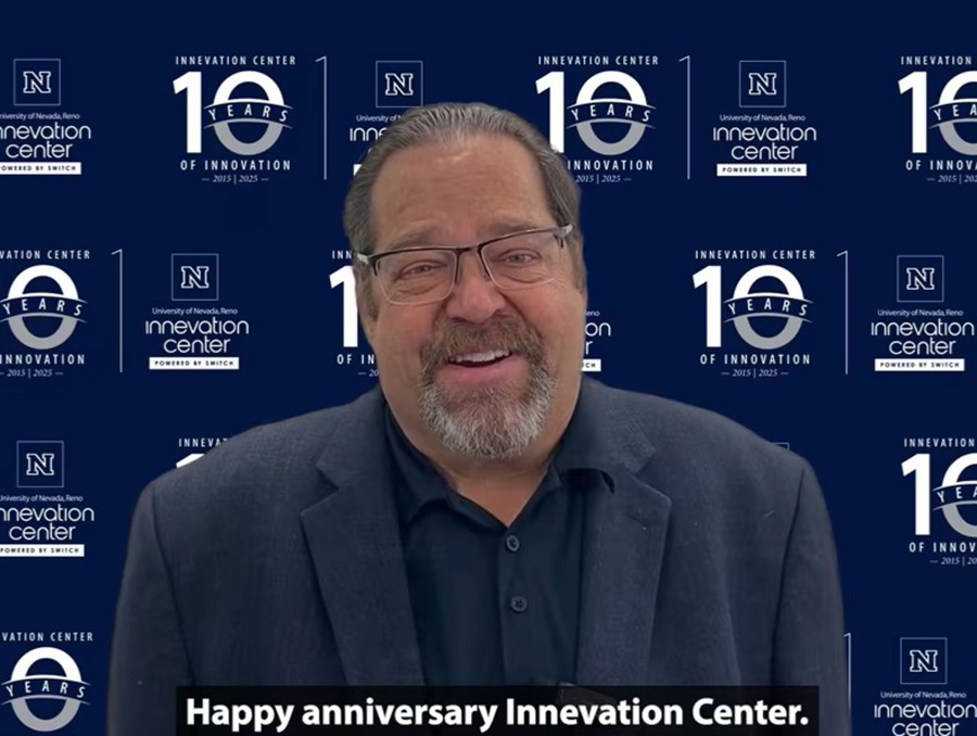 Person smiling in front of a backdrop with multiple Innovation Center logos and the text "Happy anniversary Innovation Center."