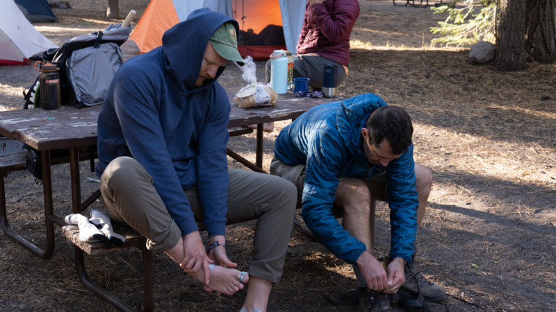 Two team members reach for their sore feet at the teams' camp.
