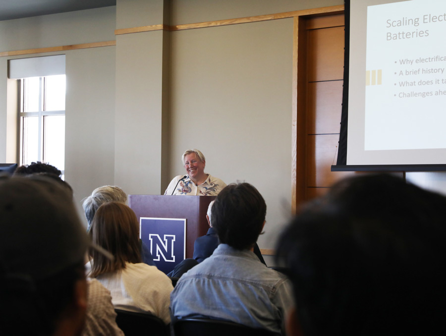 Celina Mikolajczak stands at a podium in front of an audience with a presentation behind her.
