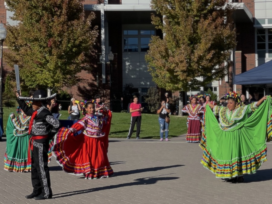 Dancers performing in front of the student union while wearing traditional baile folklórico outfits.
