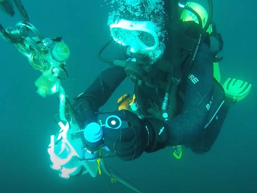A scuba diver takes a closer look at a sample while underwater.