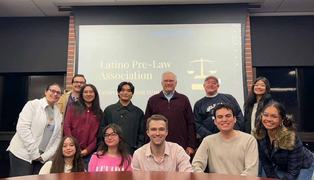 A group of students gathered around a table, smiling for the camera.