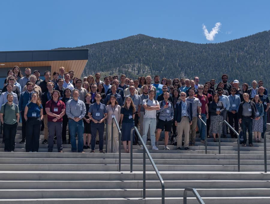 Conference participants stand on the steps outside the Tahoe Blue Event Center under a blue sky with a single cloud.