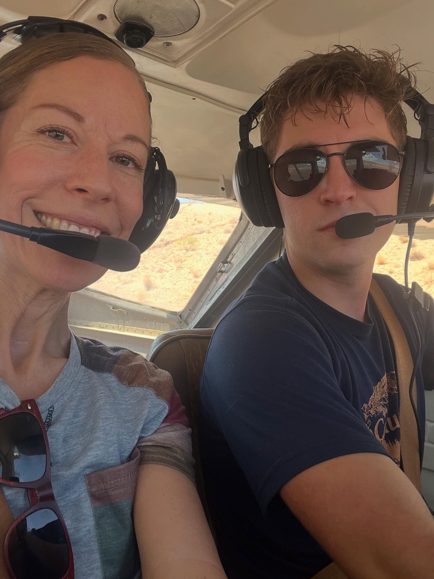 A woman and man sitting side by side in the cockpit of a plane.