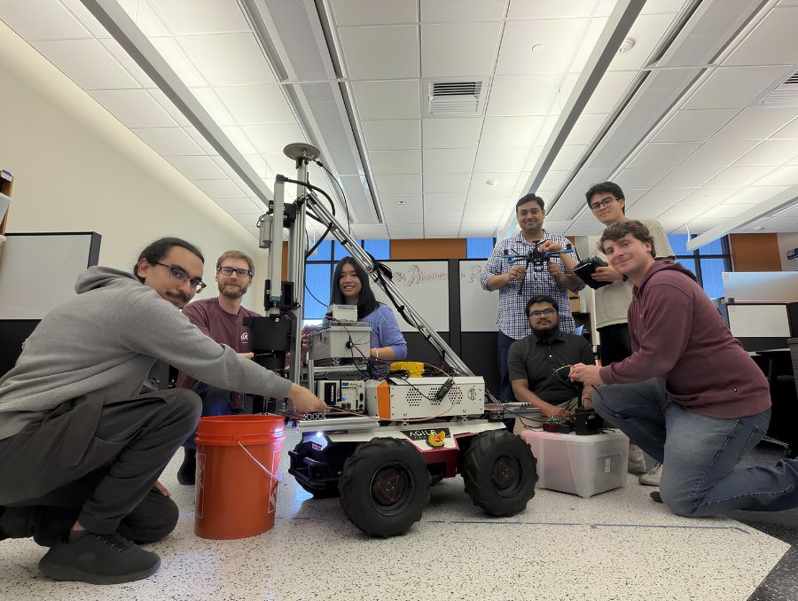 Parikshit and his students pose by a robot on wheels.