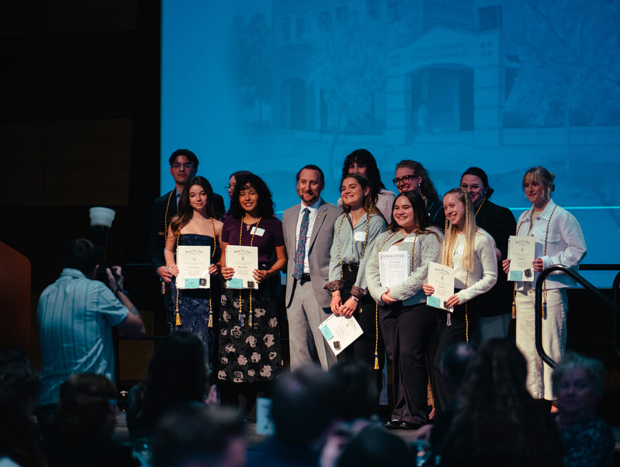 A group of students gather on stage after receiving awards. 