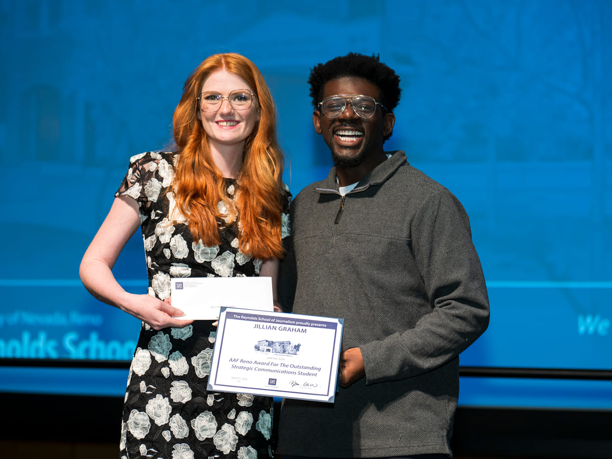 A student is presented with a certificate by a professor on stage at the awards banquet.