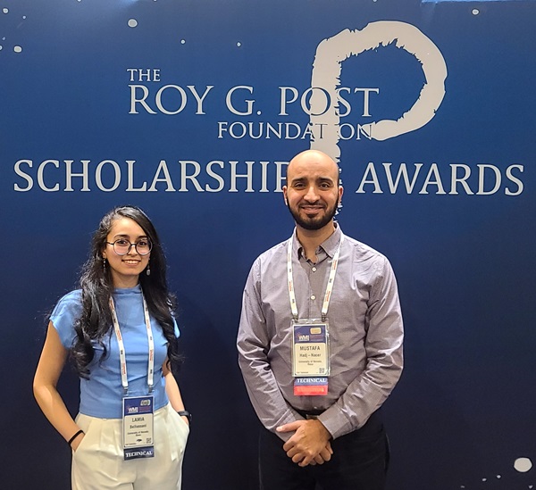 A man and a woman stand in front of a dark blue background that reads "Roy G. Post Foundation Scholarship Awards."
