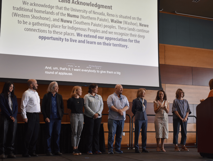 Nine individuals stand on stage during the CLA awards.