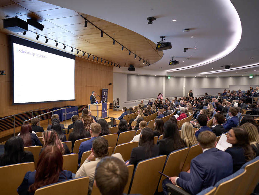 Audience seated in a large auditorium during The College of Business's Honors and Awards Ceremony presentation.