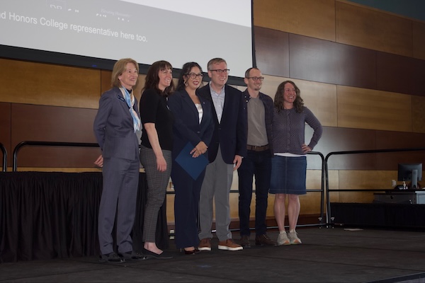 Gabby stands with a group of professors, smiling for a photo.