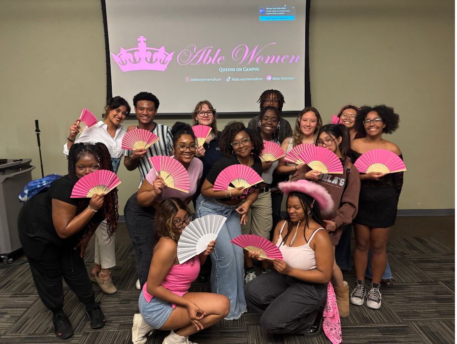 Attendees gather for a group photo, holding the fans they received at the event.