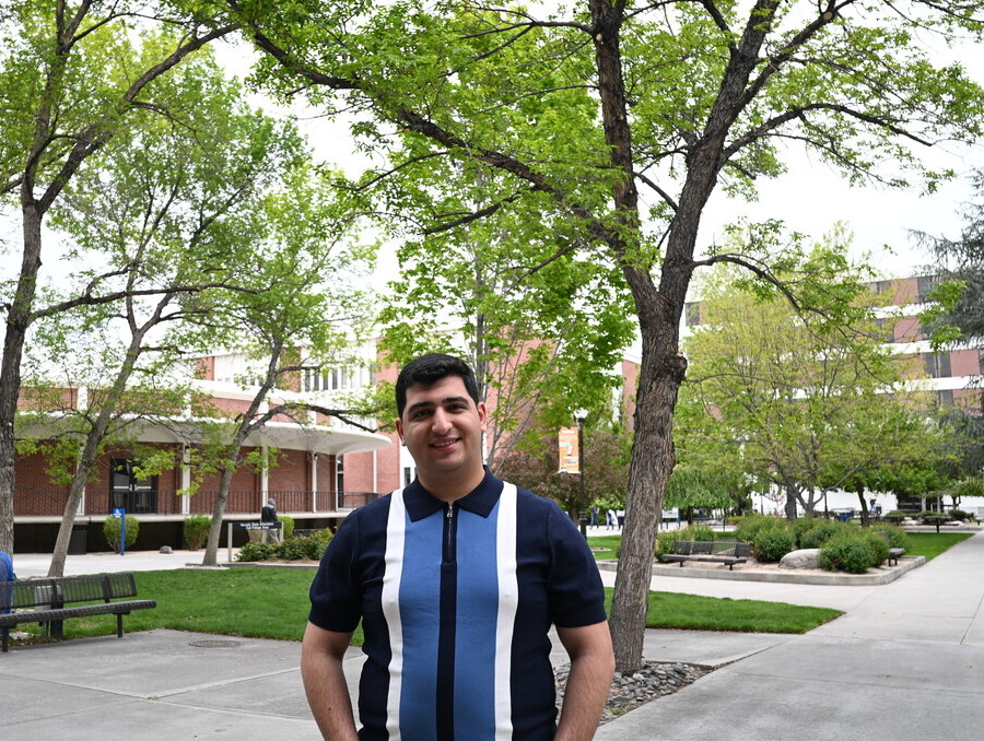 Hasanov stands on campus, smiling.