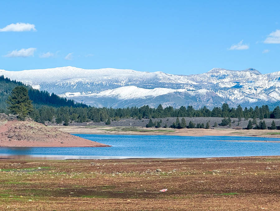 A scenic photo of snowy mountains with a dry lake in the foreground.