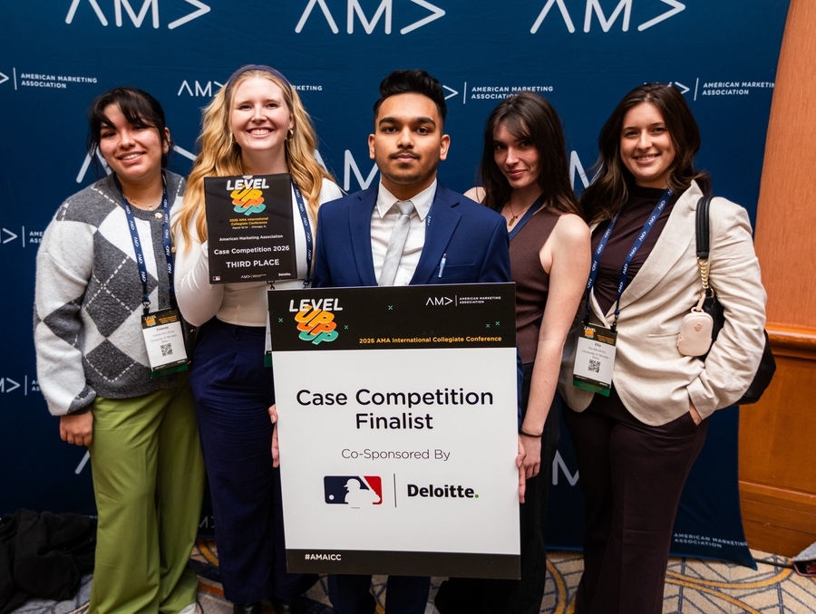 College of Business students stand together holding “Case Competition Finalist” and “Third Place” signs at the AMA Collegiate Case Competition finals.