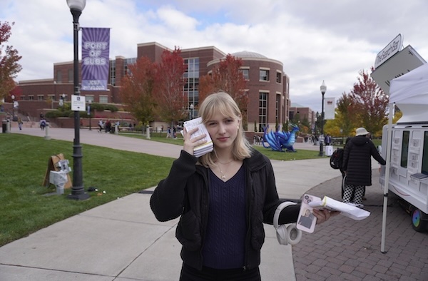 Lauren on site, holding up paper, dressed in business attire while working an event.