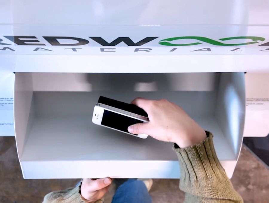 A smartphone being dropped into a recycling bin.