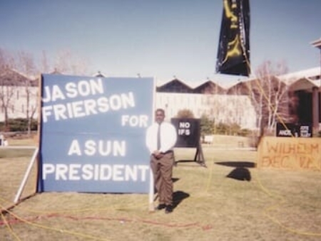 Jason Frierson standing in front of his ASUN campaign poster.